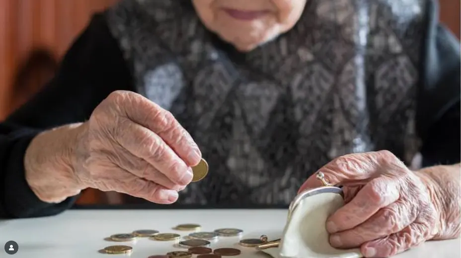 older person's hands holding coins